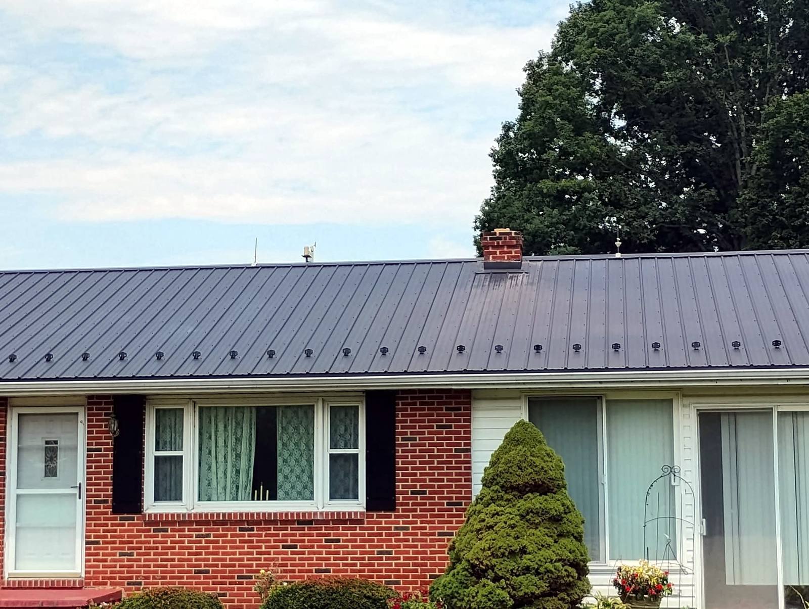 Standing-seam metal roof on a brick ranch home