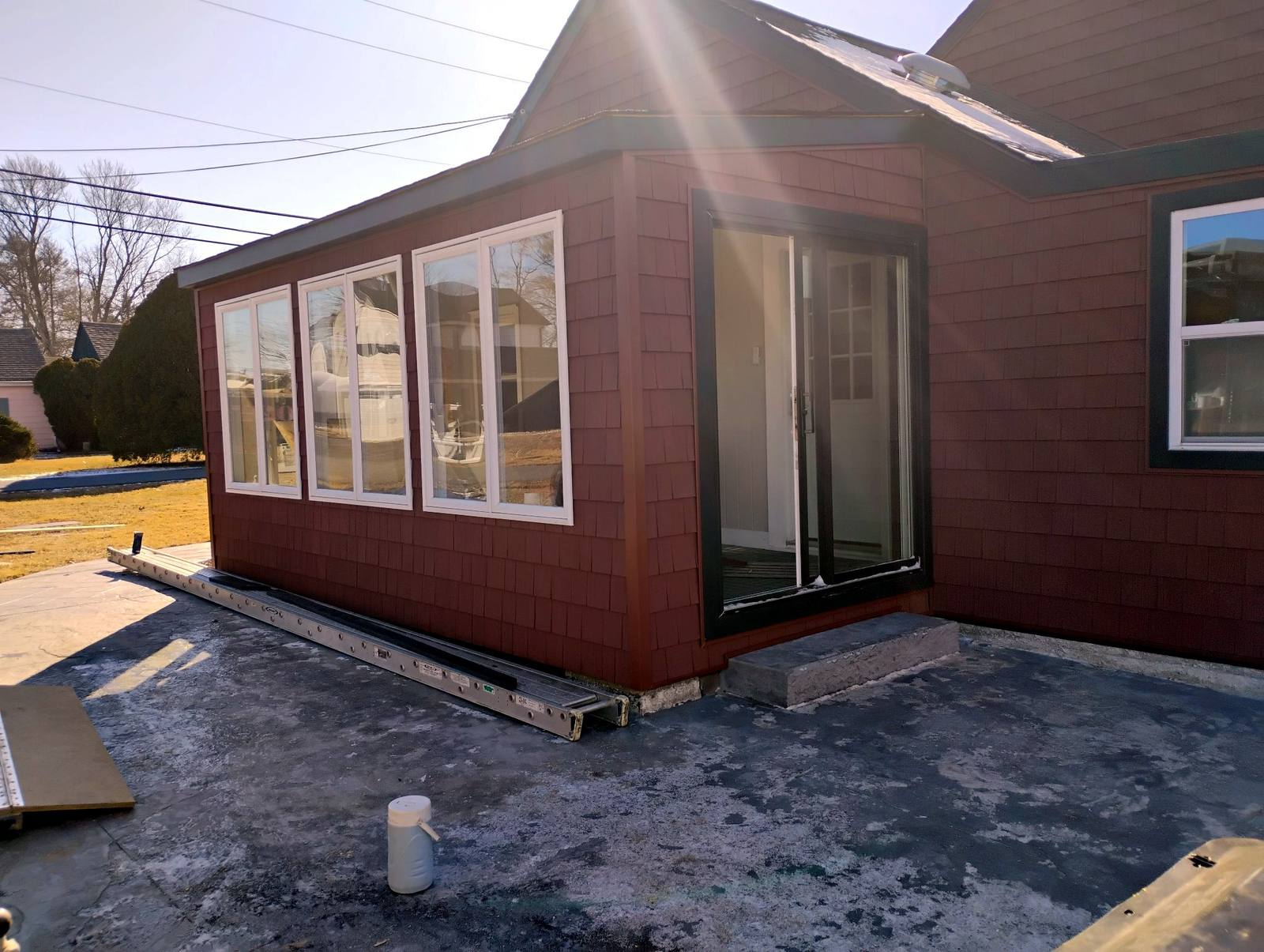 Finished sunroom addition connected to a red home