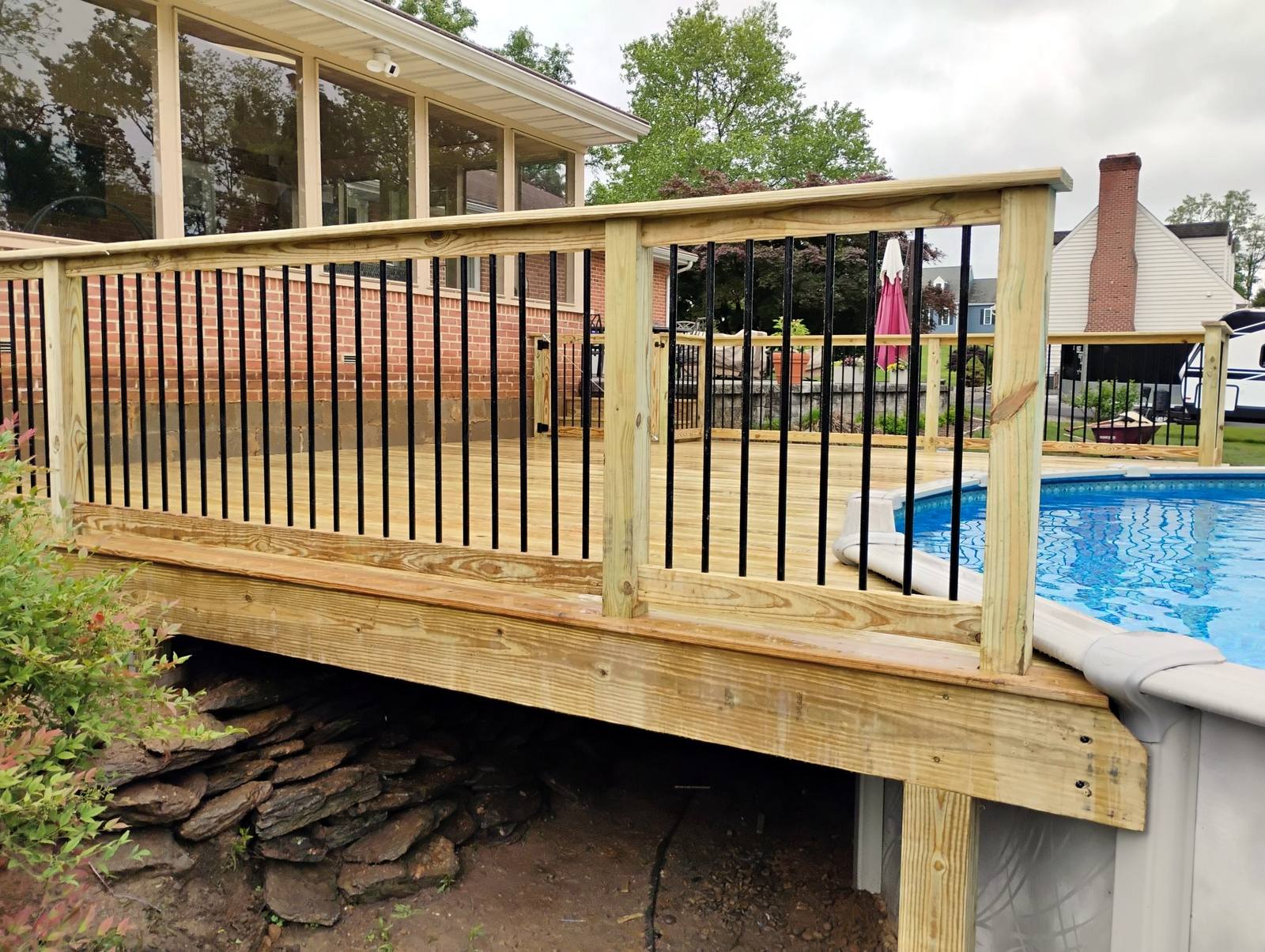 Completed wood deck wrapping an above-ground pool