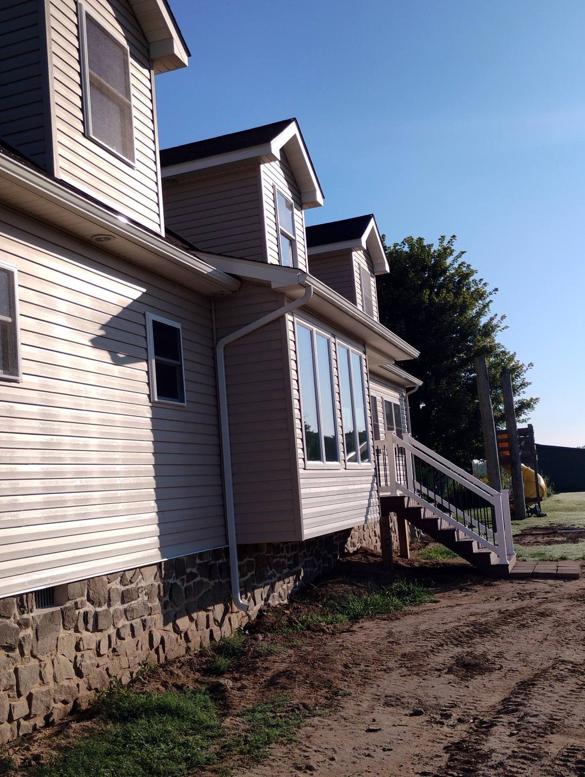 Completed home exterior with white siding and stone foundation